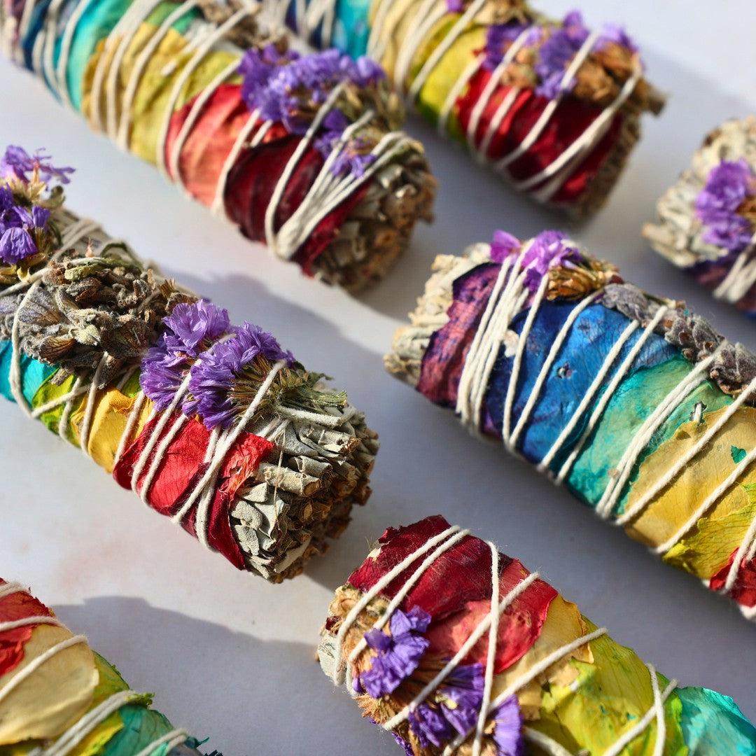 Farverige chakra salvie bundles med tørrede blomster og urter bundet med snor på en lys overflade