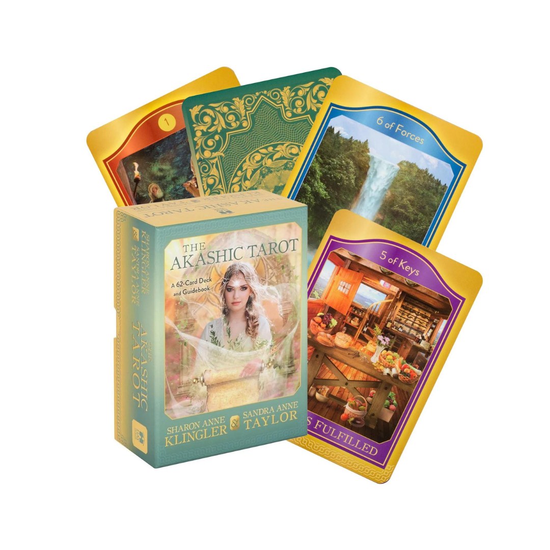 Pakke af Akashic Tarot kort med en kvindelig skikkelse på forsiden og flere kort, der viser farverige illustrationer og symbolske billeder såsom vandfald og interiør fra en butik.