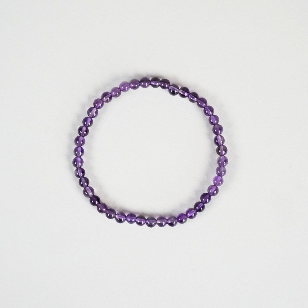 Ametyst armbånd med 4 mm perler i nuancer af lilla sat på en hvid baggrund