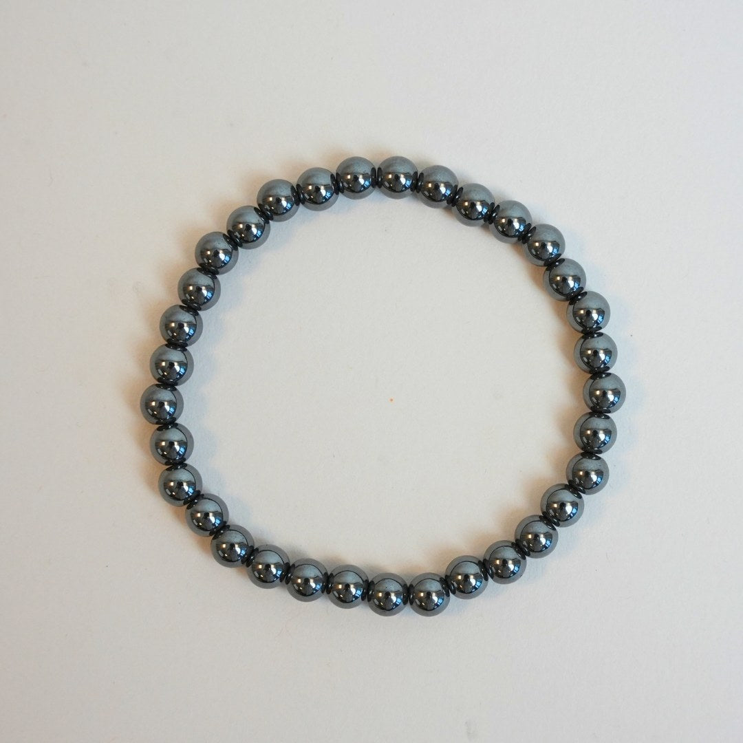Hæmatit armbånd skabt af glinsende grå perler der danner en cirkel