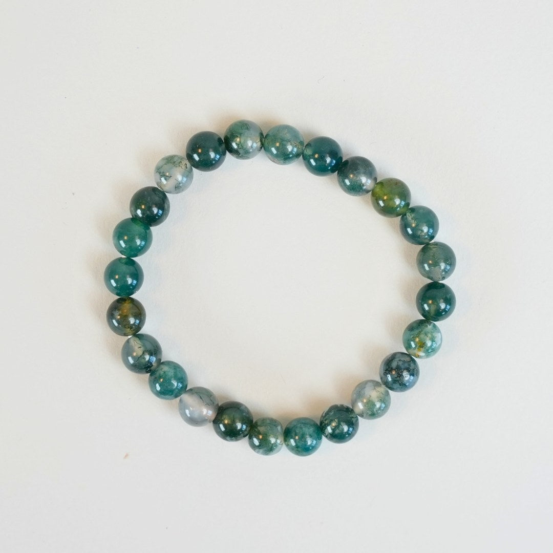 Mos agat armbånd lavet af glinsende grønne og blå perler i forskellige nuancer arrangeret i en rund form