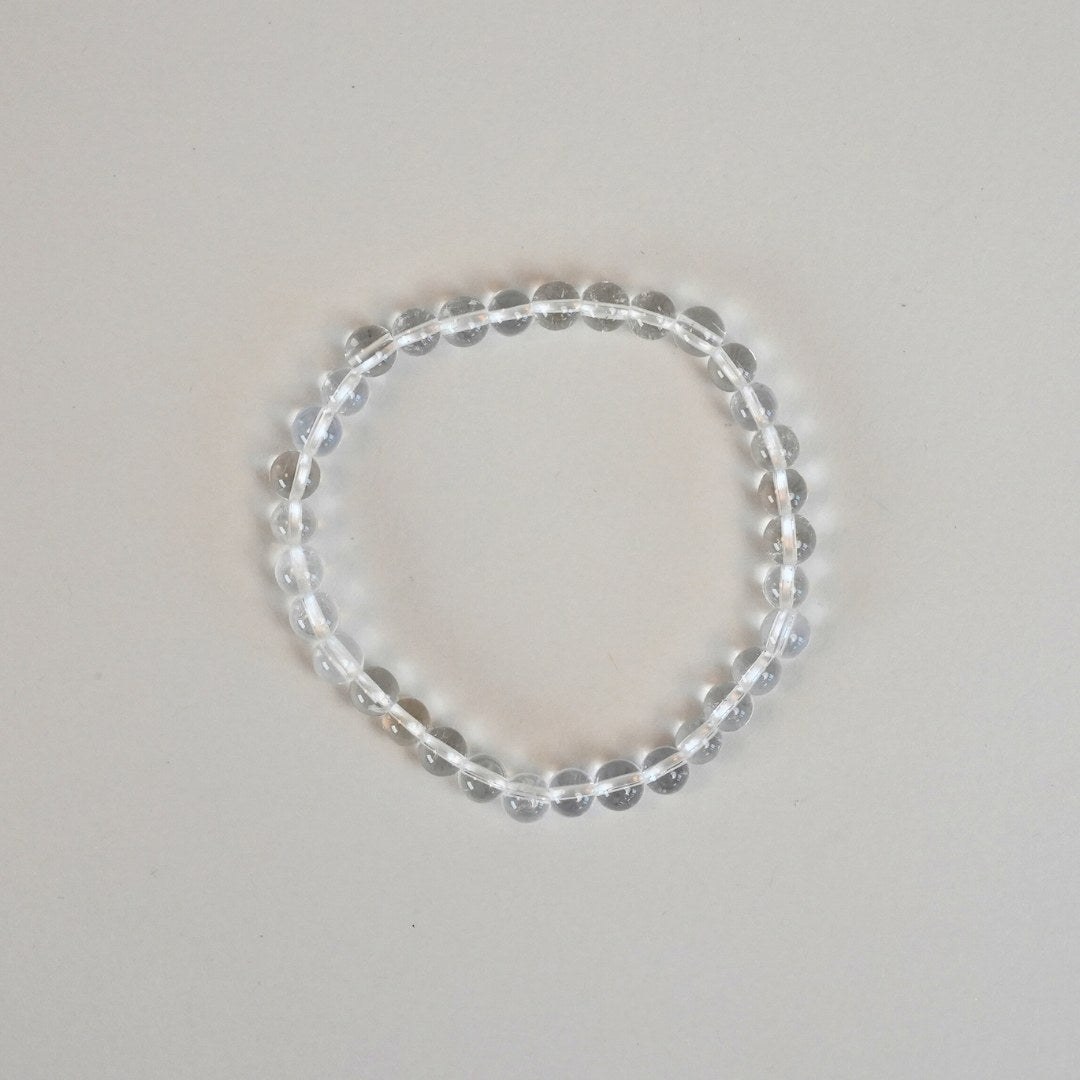 Bjergkrystal armbånd bestående af klare, glansfulde perler i en cirkulær form på en neutral baggrund