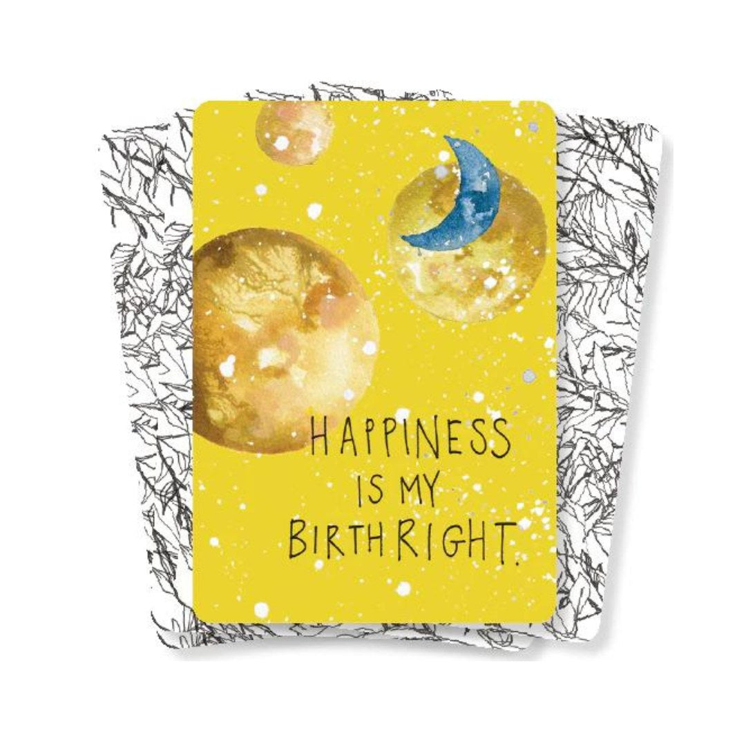 Produktbillede af orakelkortene The Universe Has Your Back med en gul baggrund, der indeholder vandfarveillustrationer af måner og planeter samt teksten Happiness is my birthright i sort skrift