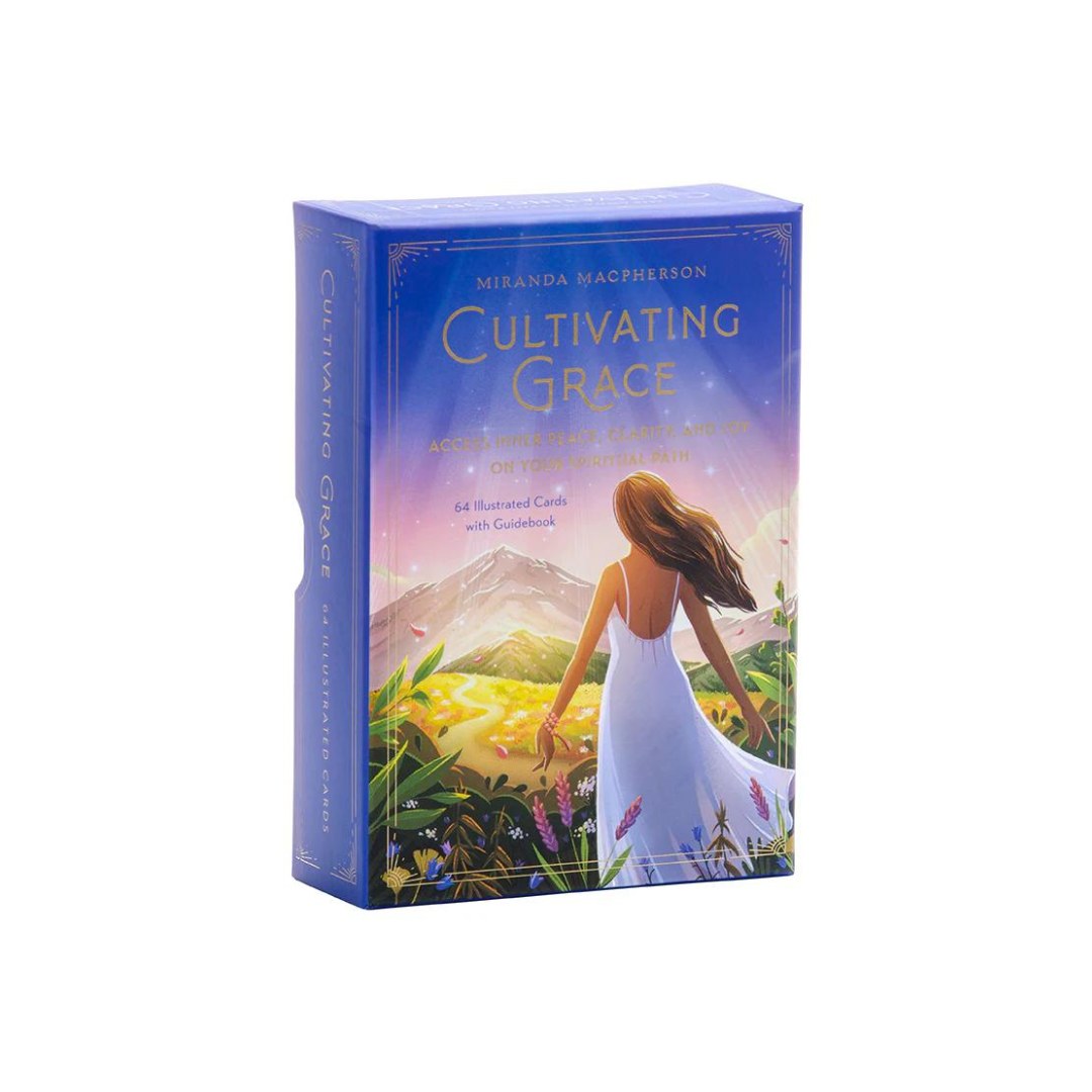 Produktpakke med titlen Cultivating Grace af Miranda Macpherson viser en smuk illustration af en kvinde i en hvid kjole som skuer ud over en frodig dal med bjerge i baggrunden boksen indeholder 64 illustrerede kort og en vejledning til åndelig udvikling