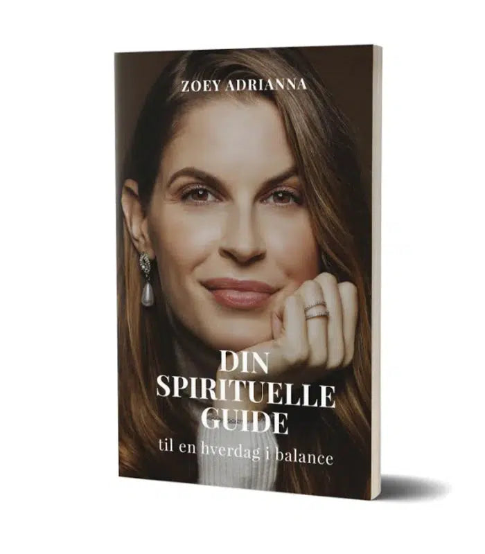 Bogforside med titlen Din Spirituelle Guide til en hverdag i balance skrevet af Zoey Adrianna med et nærbillede af en kvinde der smiler og har lange bølgeret hår samt øreringe