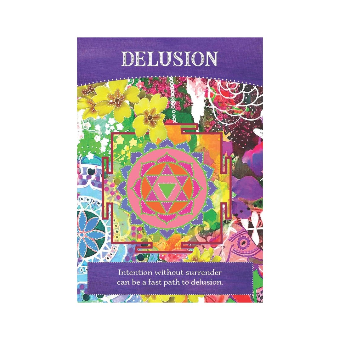 Kortet 'Delusion' fra serien Divine Abundance præsenterer et farverigt design med blomster og mønstre i nuancer af lilla, grøn, pink og gult samt en central mandala med et trekantet symbol. Nederst står teksten 'Intention without surrender can be a fast path to delusion' på en lilla baggrund.