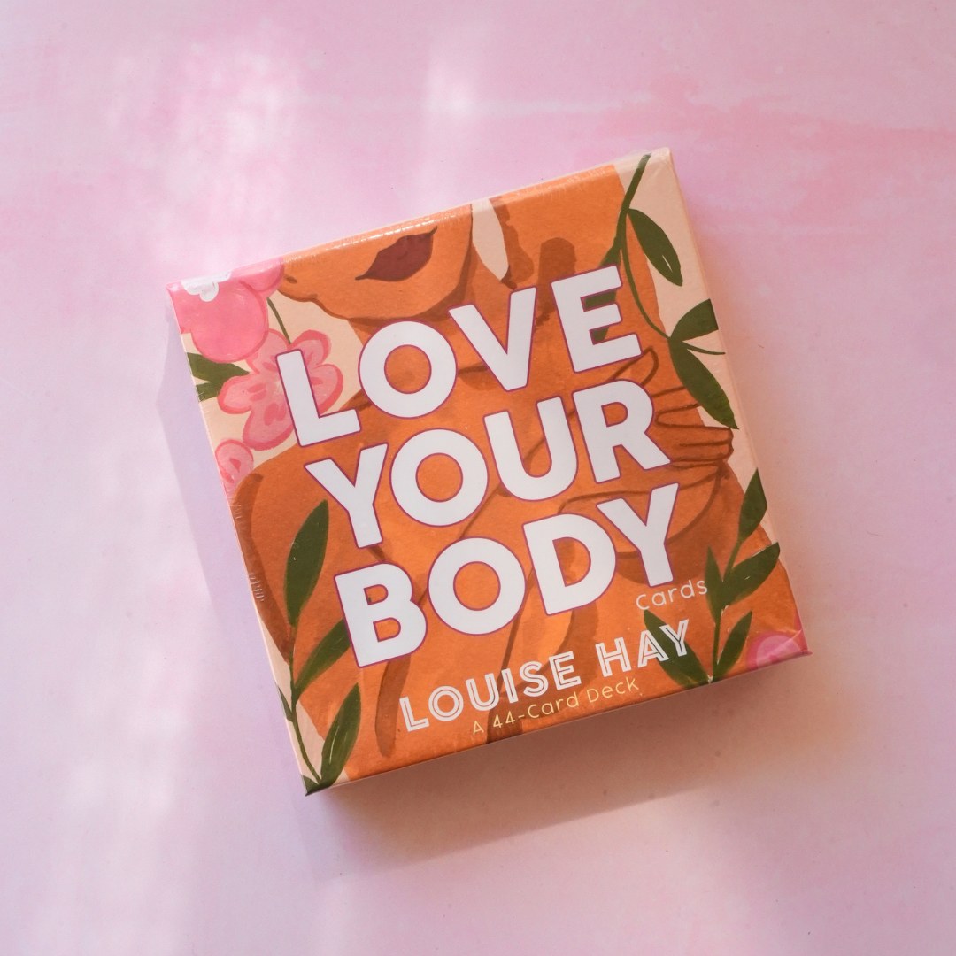 Produktet Love your body orakelkort præsenterer en farverig æske med blomsterdesign og store, tydelige bogstaver der fremhæver titlen og forfatterens navn Louise Hay og angiver at det er et 44-korts spil