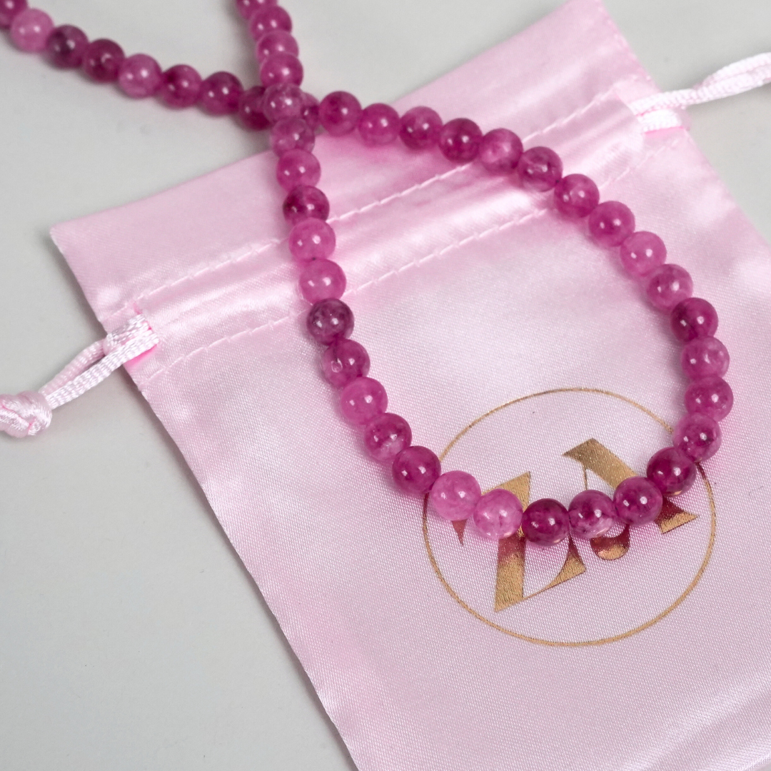 DIVINE halskæde i smuk rosa farve lavet af glatte perler præsenteret på en lyserød stofpose med et gyldent logo
