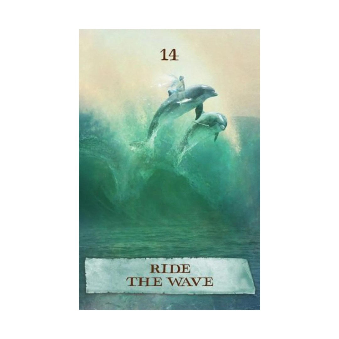 Kort nummer 14 fra The Enchanted Map orakelkort med teksten Ride The Wave og et billede af to delfiner, der hopper over en stor grøn bølge med en drømmer på ryggen, der symboliserer frihed og eventyr.