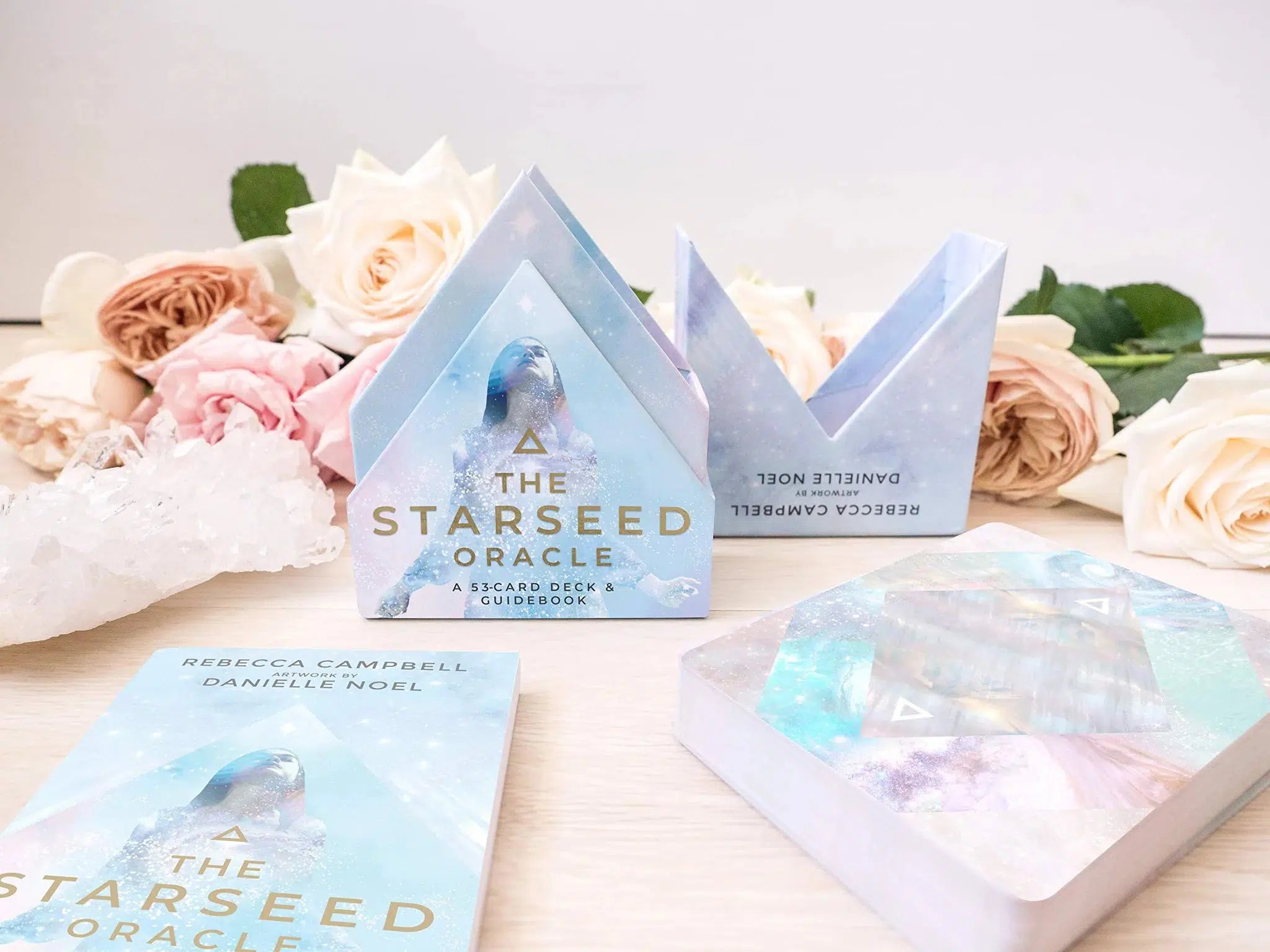 Stjernesjæl af Rebecca Campbell orakelkort præsenteret med kort og guidebog i et lysende design med pastelfarver og en illustration af en kvinde med en stjerneagtig baggrund omringet af roser og krystaller